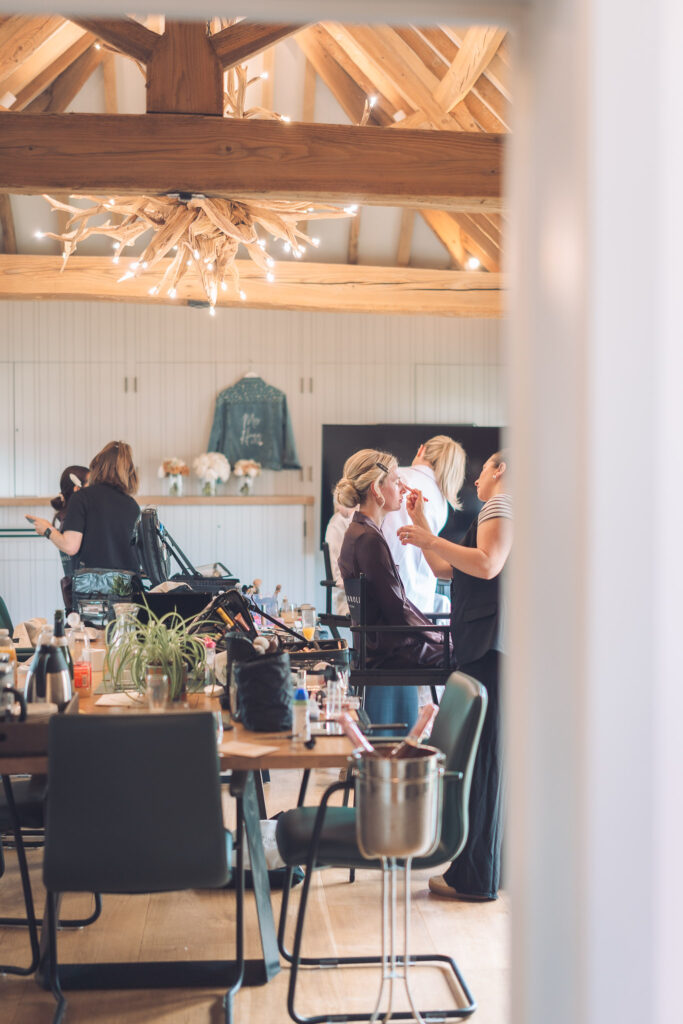 Bridal party preparing hair and make up in light room with wooden beams