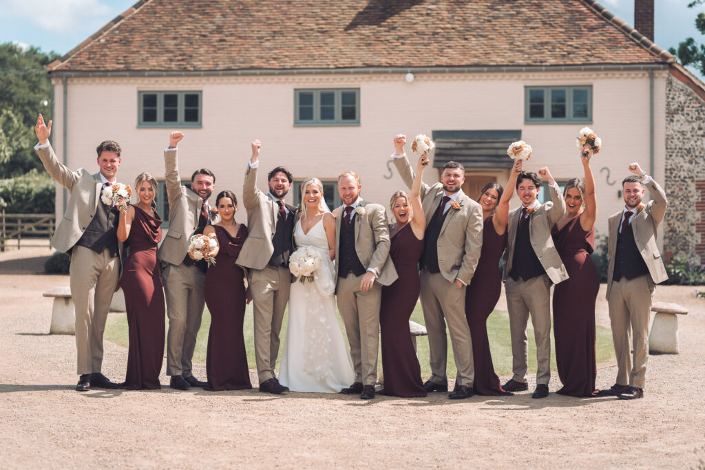 Bride and groom smiling as bridesmaids and groomsmen cheer around them