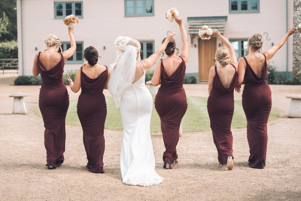 Bridal party jubilantly walking away from camera with arms aloft