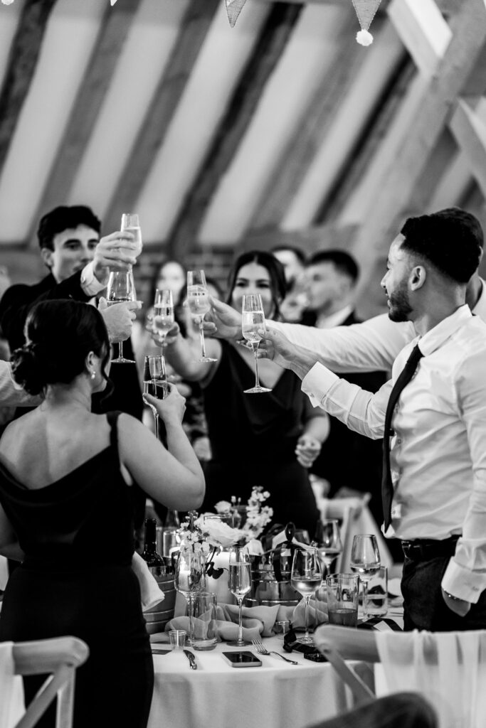Wedding guests standing to toast bride and groom with flutes of champagne